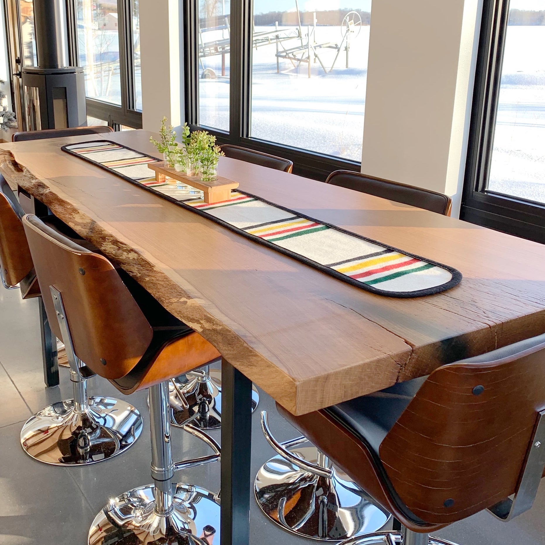 Custom made live-edge conference tabletop on metal base with leather barstools.