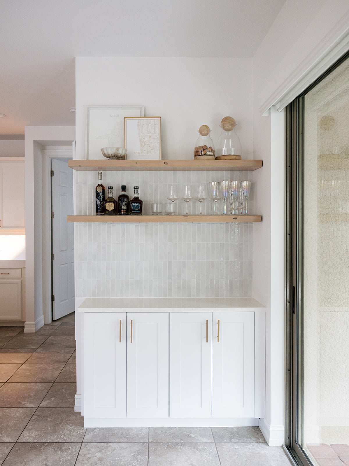 Modern kitchen with white cabinets, wooden shelves, and decorative items. Dakota Timber Co floating shelf kit. Khaki, light tan, natural wood floating shelves. Photo by Rachel Platt.