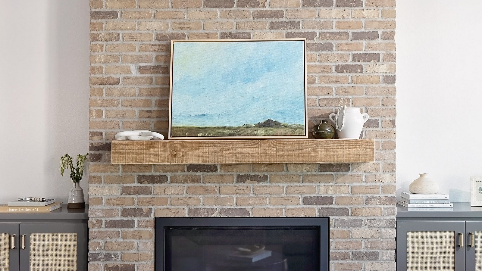 Brick fireplace with a canvas mounted above it in a living room setting.