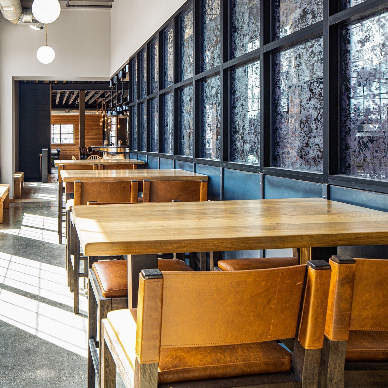 Light wood restaurant table tops with mustard yellow leather chairs in Scandinavian inspired Fargo,ND restaurant.